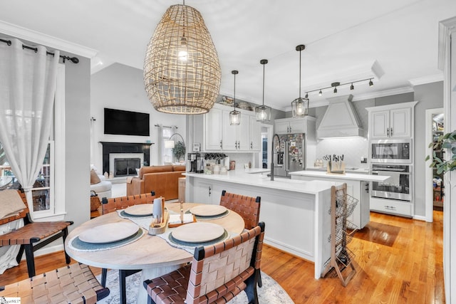 dining area with crown molding, a fireplace, and light wood-type flooring