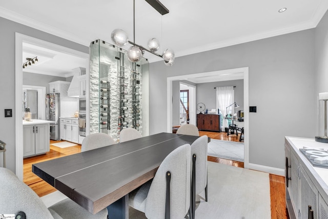dining room with baseboards, crown molding, and light wood finished floors