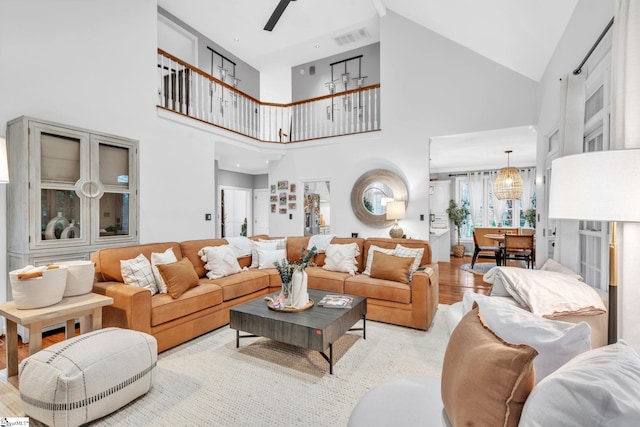 living area with visible vents, lofted ceiling, wood finished floors, and a ceiling fan