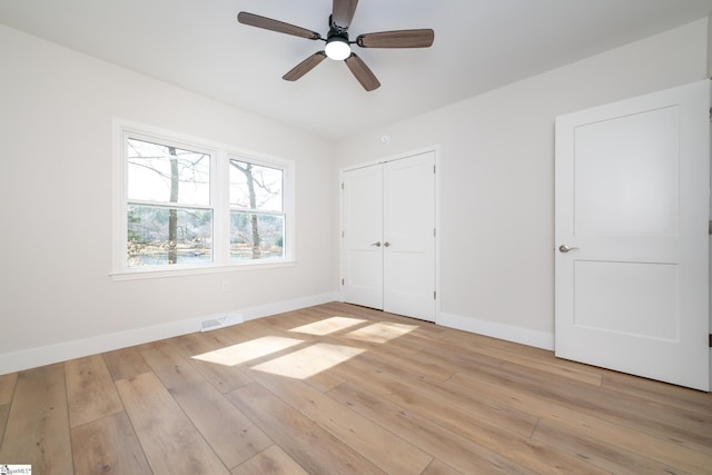 unfurnished bedroom with visible vents, light wood-style flooring, a closet, baseboards, and ceiling fan