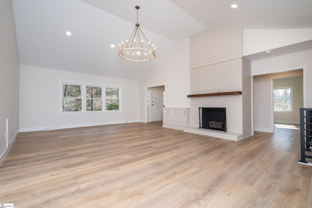 unfurnished living room featuring visible vents, a brick fireplace, light wood-style floors, an inviting chandelier, and high vaulted ceiling