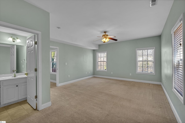 spare room with baseboards, light colored carpet, visible vents, and ceiling fan