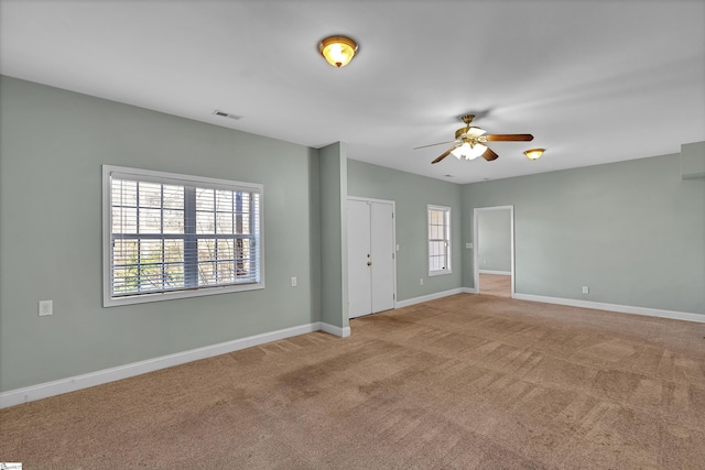 carpeted empty room featuring a ceiling fan, visible vents, and baseboards