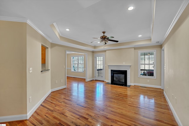unfurnished living room with a raised ceiling, light wood-type flooring, and ceiling fan