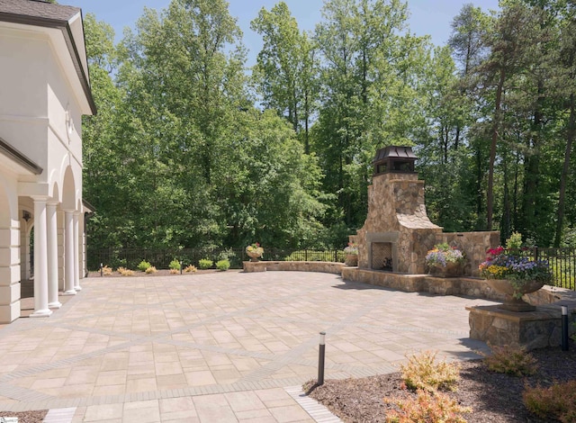 view of patio featuring an outdoor stone fireplace and fence