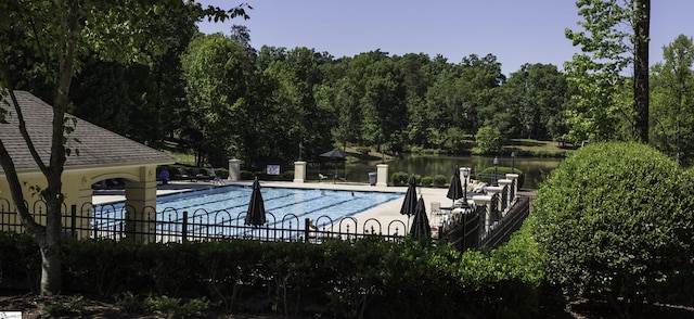 pool featuring fence, a patio, and a water view