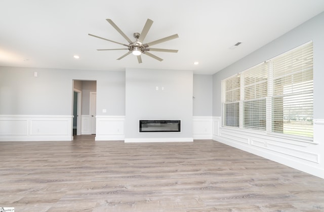 313 Barker Rd, Simpsonville, SC 29680 - unfurnished living room featuring a glass covered fireplace, wood finished floors, recessed lighting, wainscoting, and ceiling fan