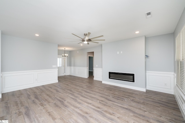 313 Barker Rd, Simpsonville, SC 29680 - unfurnished living room with visible vents, ceiling fan with notable chandelier, wood finished floors, and a glass covered fireplace