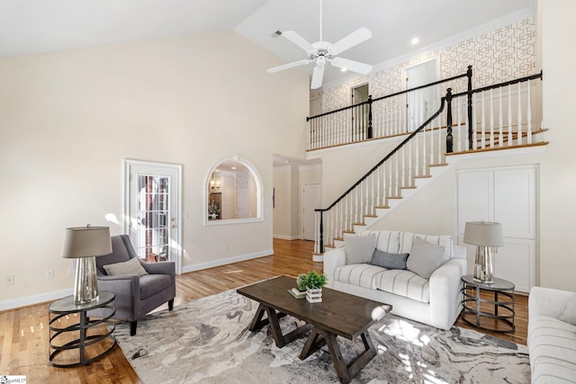 living area with stairway, baseboards, high vaulted ceiling, and wood finished floors