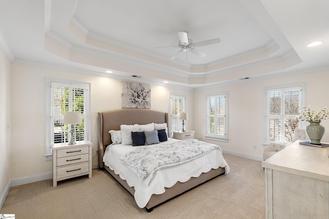 bedroom featuring light carpet, multiple windows, a raised ceiling, and baseboards