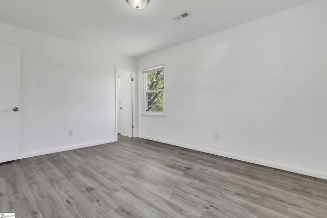 empty room featuring visible vents, baseboards, and wood finished floors