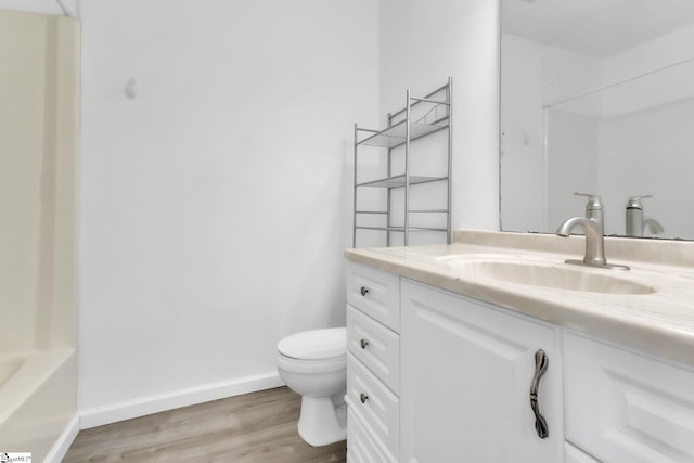 bathroom with walk in shower, baseboards, toilet, wood finished floors, and vanity