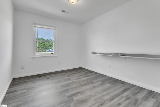 unfurnished room with wood finished floors, visible vents, and baseboards