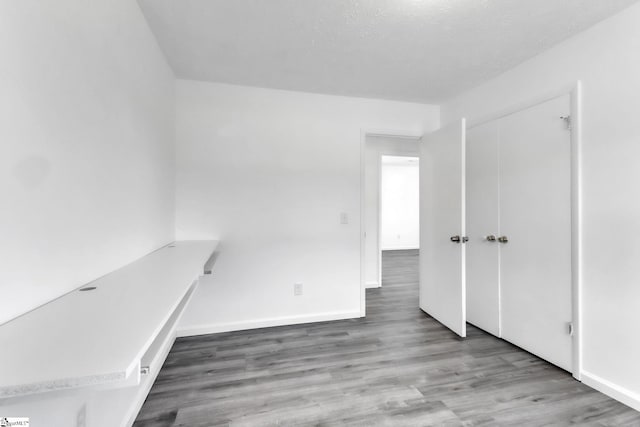 interior space featuring baseboards, a textured ceiling, and wood finished floors