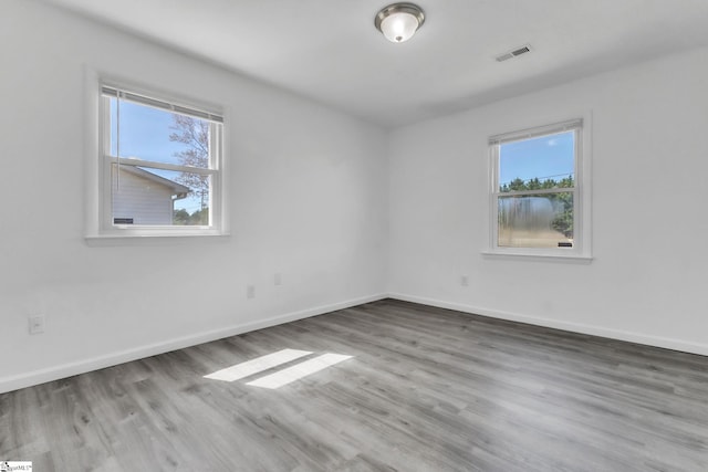 unfurnished room featuring visible vents, baseboards, and wood finished floors