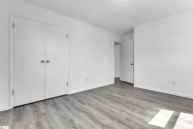 unfurnished bedroom with a closet, baseboards, and wood finished floors