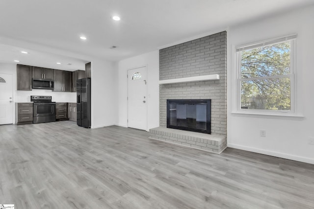 unfurnished living room featuring recessed lighting, a brick fireplace, baseboards, and light wood-style floors
