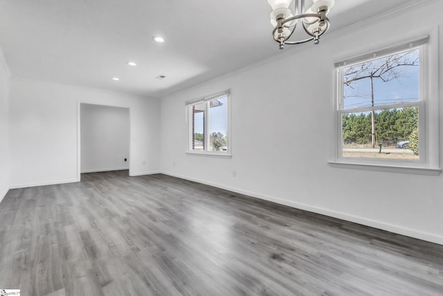 unfurnished room featuring an inviting chandelier, crown molding, wood finished floors, and baseboards