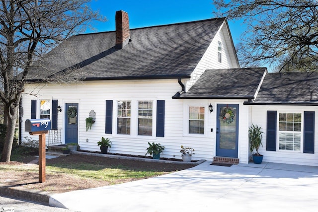 cape cod house featuring a chimney, entry steps, and a shingled roof