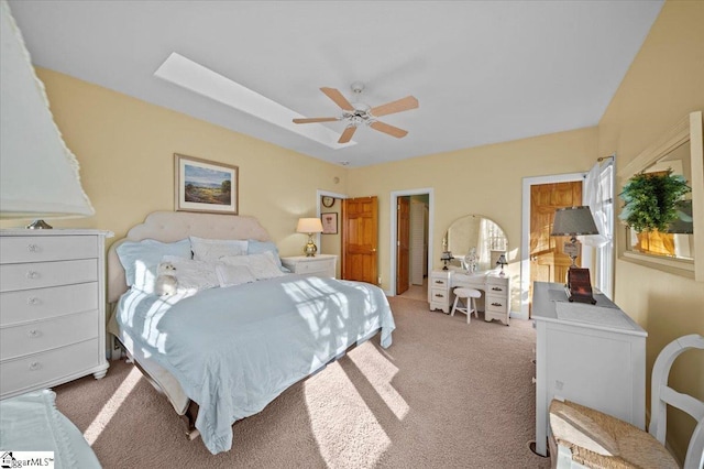 bedroom featuring a tray ceiling, light colored carpet, and ceiling fan