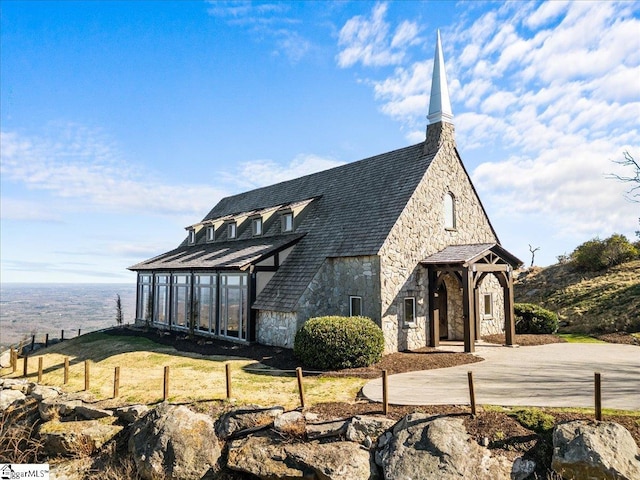 view of front of property featuring concrete driveway, fence, and stone siding