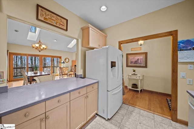 kitchen featuring freestanding refrigerator, recessed lighting, an inviting chandelier, a skylight, and light floors