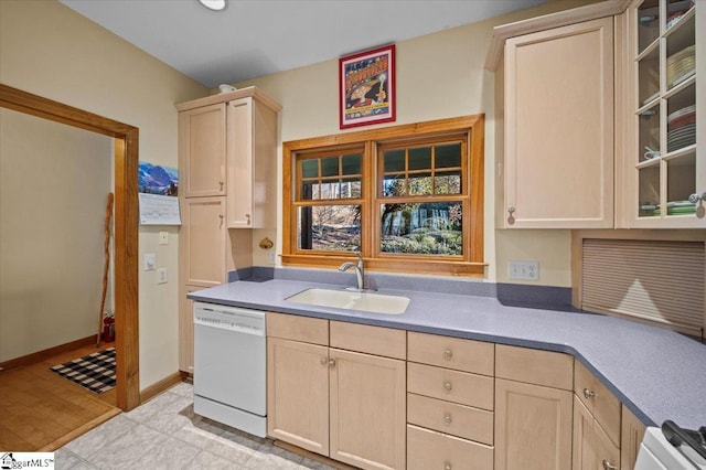 kitchen featuring dishwasher, baseboards, light brown cabinetry, and a sink