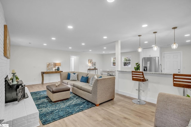 living area with a fireplace, recessed lighting, light wood-style floors, and baseboards