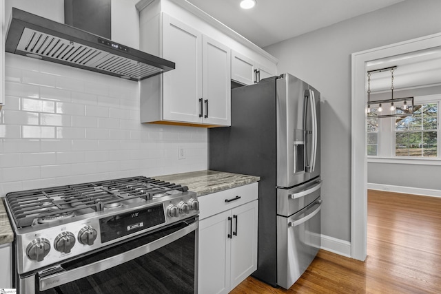 510 N Franklin Rd, Greenville, SC 29609 - kitchen with backsplash, wall chimney range hood, light wood-type flooring, appliances with stainless steel finishes, and white cabinets