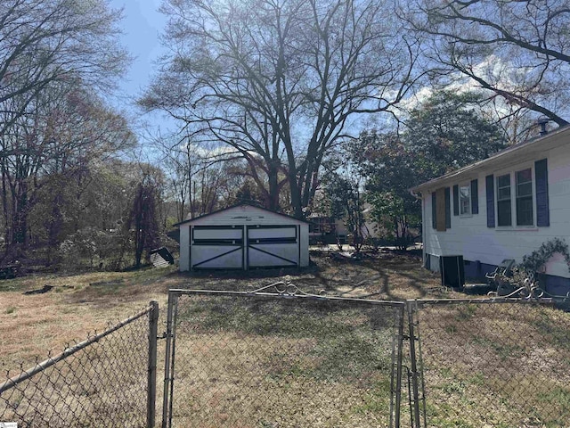 view of yard with a gate, a detached garage, a shed, fence, and an outdoor structure