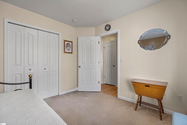 carpeted bedroom with a closet and baseboards
