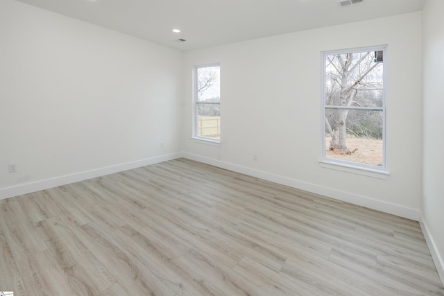 unfurnished room featuring visible vents, wood finished floors, and baseboards