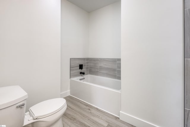 full bathroom with a bath, toilet, baseboards, and wood finished floors