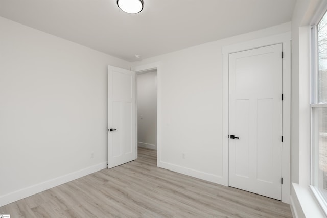 unfurnished bedroom featuring light wood-type flooring and baseboards