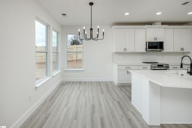 kitchen featuring a sink, visible vents, stainless steel electric range, and a chandelier