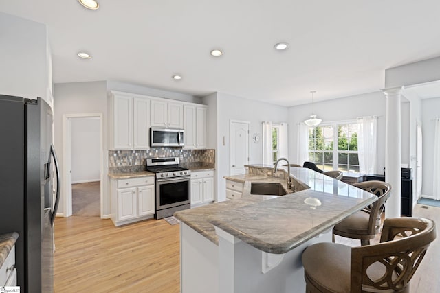39 Santee Ct, Simpsonville, SC 29680 - kitchen featuring a sink, a kitchen breakfast bar, light wood-style floors, appliances with stainless steel finishes, and decorative backsplash