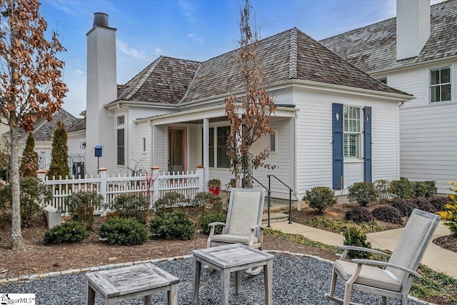 rear view of property featuring a chimney and fence