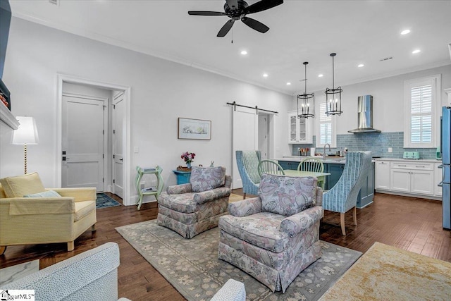 living room with crown molding, a barn door, dark wood-style floors, ceiling fan, and recessed lighting