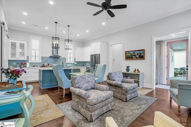 living area featuring dark wood-style floors, ceiling fan, ornamental molding, and baseboards