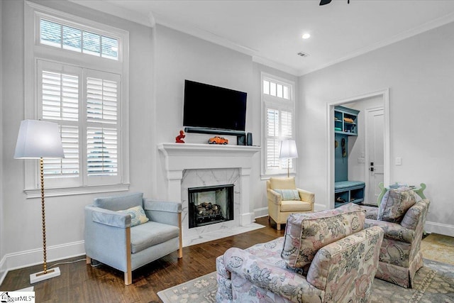 living area with ornamental molding, baseboards, visible vents, a fireplace, and wood finished floors