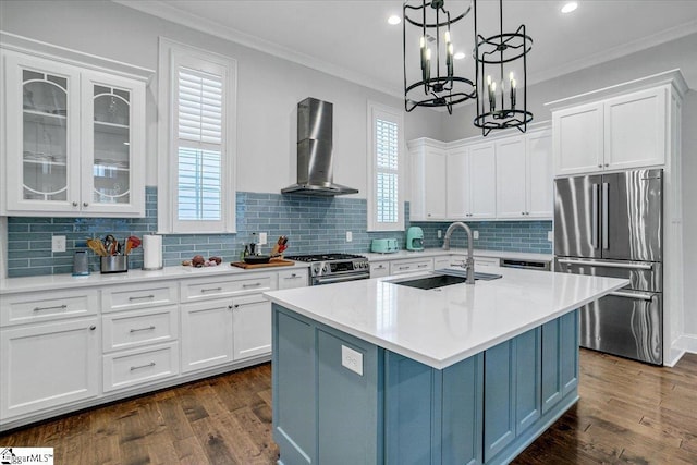 kitchen with a sink, wall chimney range hood, crown molding, and appliances with stainless steel finishes