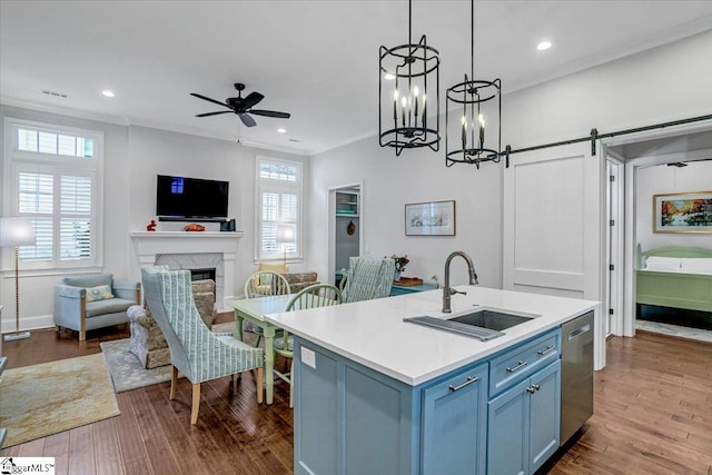 kitchen with ornamental molding, a sink, stainless steel dishwasher, and blue cabinetry