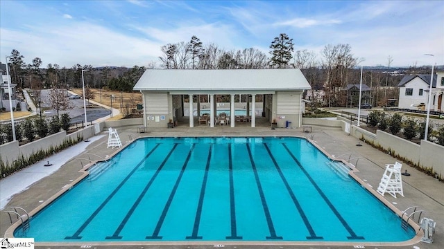 pool featuring fence, an outdoor structure, and a patio area