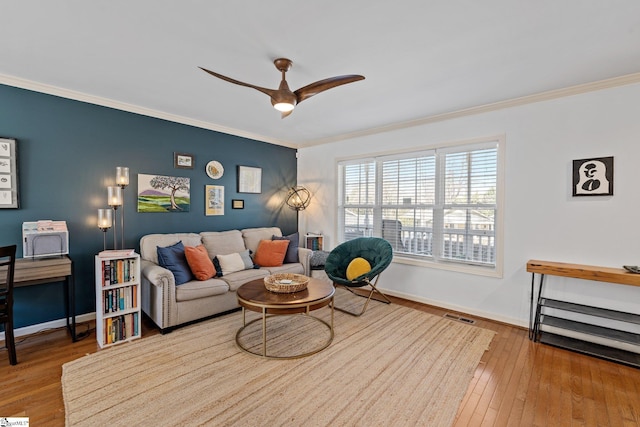 living area with visible vents, wood-type flooring, ornamental molding, and a ceiling fan