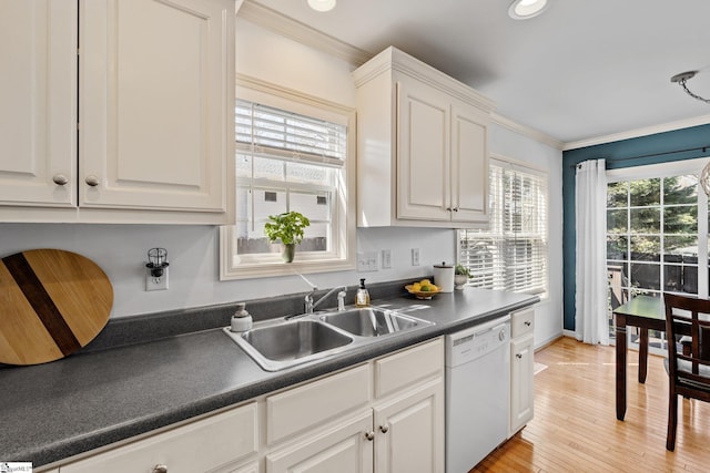 kitchen featuring dark countertops, ornamental molding, dishwasher, and a sink