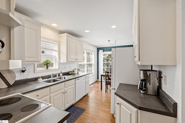 kitchen with a wealth of natural light, light wood-style floors, dark countertops, and white dishwasher