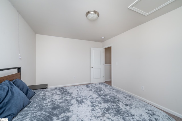 unfurnished bedroom with attic access, carpet flooring, and baseboards