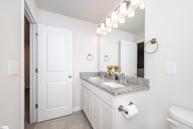 bathroom with a sink, toilet, double vanity, and tile patterned flooring