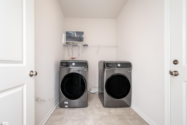 laundry room with laundry area, light tile patterned flooring, washing machine and dryer, and baseboards