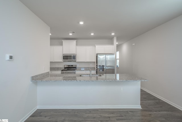 kitchen featuring a sink, appliances with stainless steel finishes, white cabinetry, and light stone countertops
